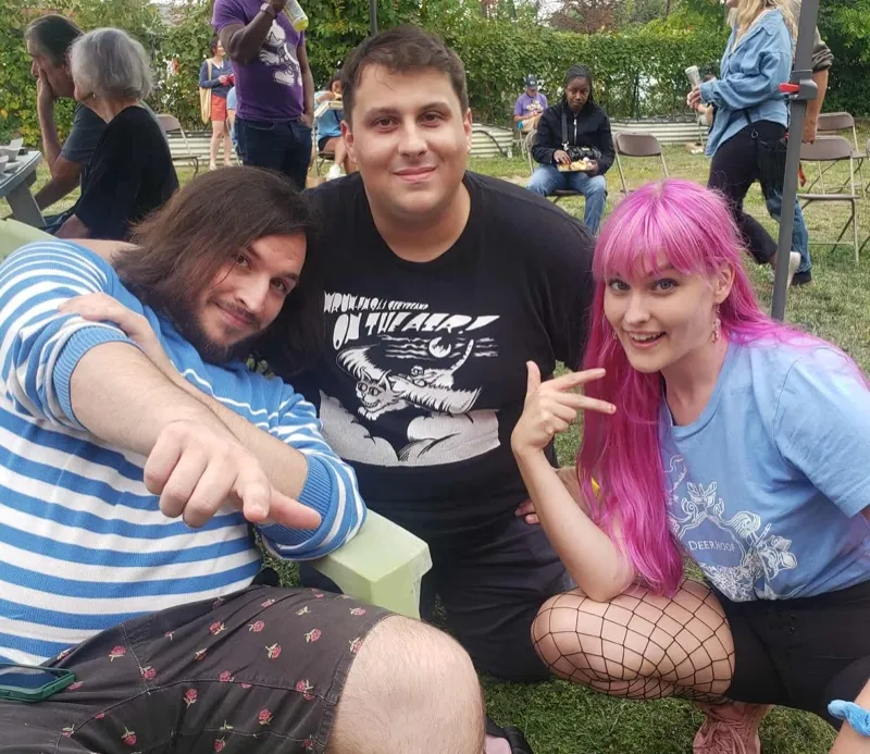 Three members of Dead Links sitting together outdoors.